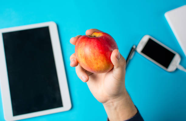 istock Hand holding an apple with tablet and cell phone 654680454