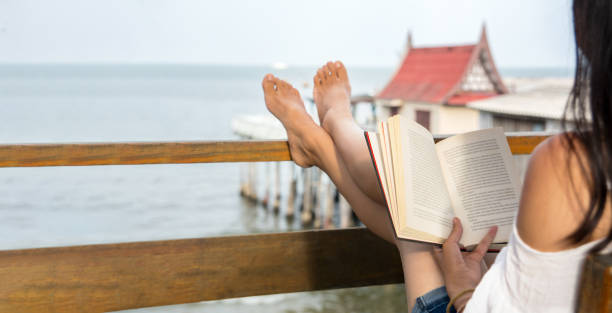Girl reading a book on the balcony with seaside view