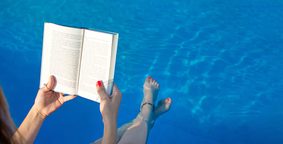 Girl reading by the swimming pool. Summer literature