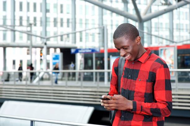 istock Cheerful black guy using smart phone at railway station 654703540