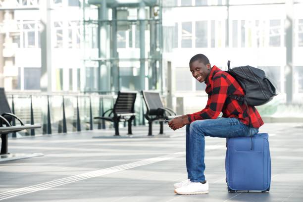 istock Happy black guy sitting on bag at train station 654703678