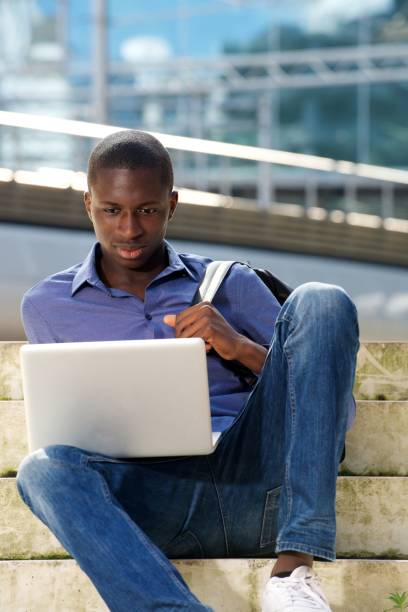 istock Young african man sitting outdoors and using laptop 654703730