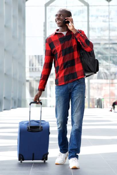 istock Smiling travel man walking with suitcase and talking on mobile phone 654703742