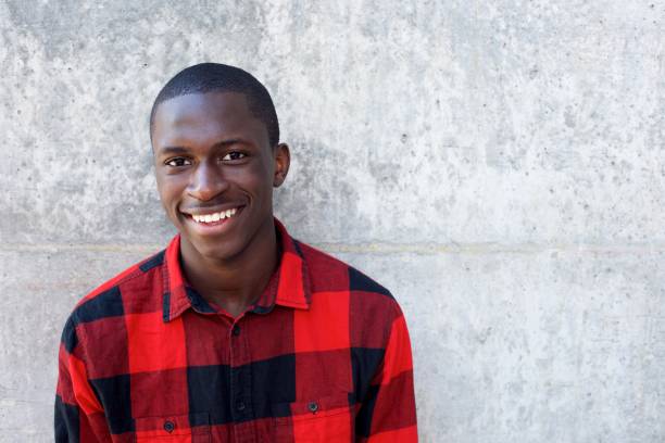 istock Smiling young african male model standing against wall 654703898