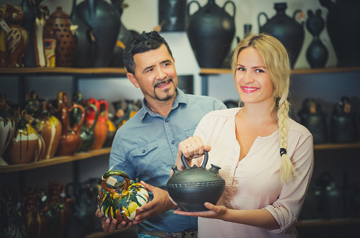 Man and woman selecting unpainting or colorful pot in workshop