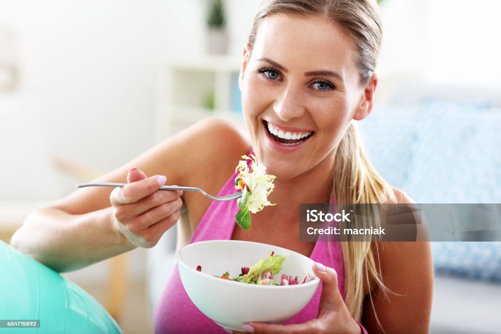 Mujer joven comer ensalada saludable después de entrenamiento - Foto de stock de Comida sana libre de derechos