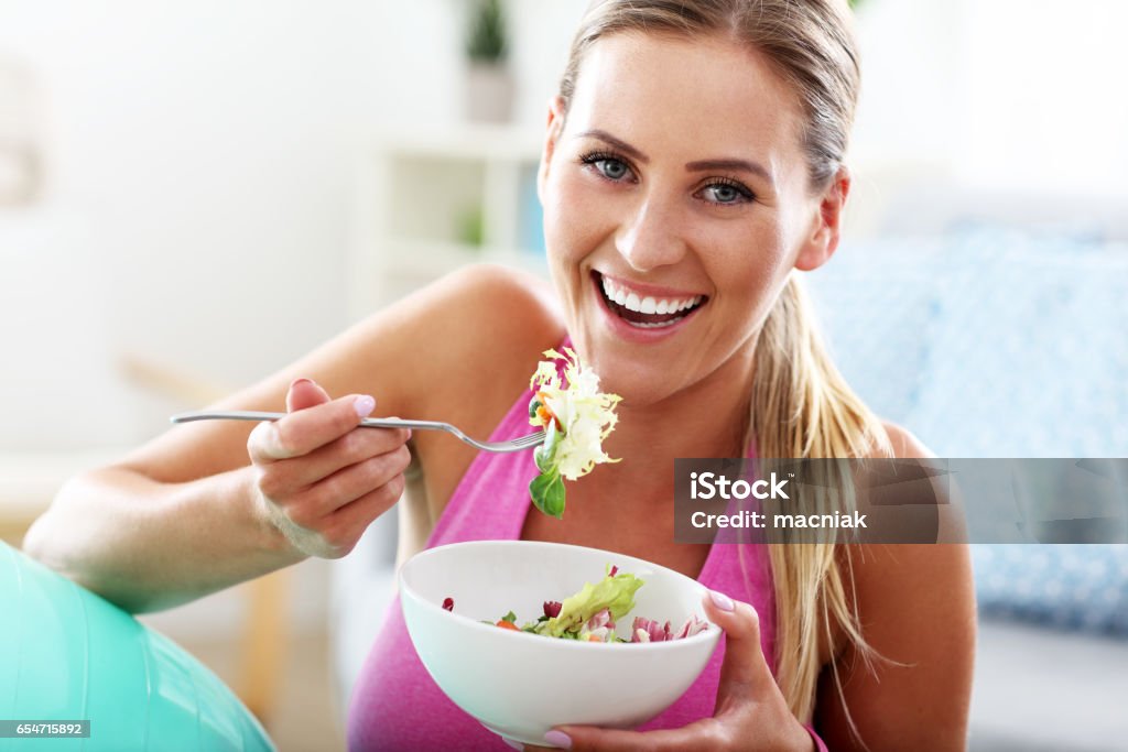 Young woman eating healthy salad after workout Fit woman eating healthy salad after workout Healthy Eating Stock Photo