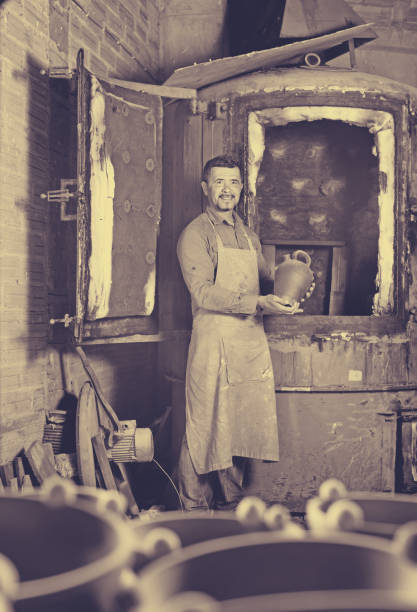 istock Cheerful craftsman carrying fresh baked black glazed vessel 654715986