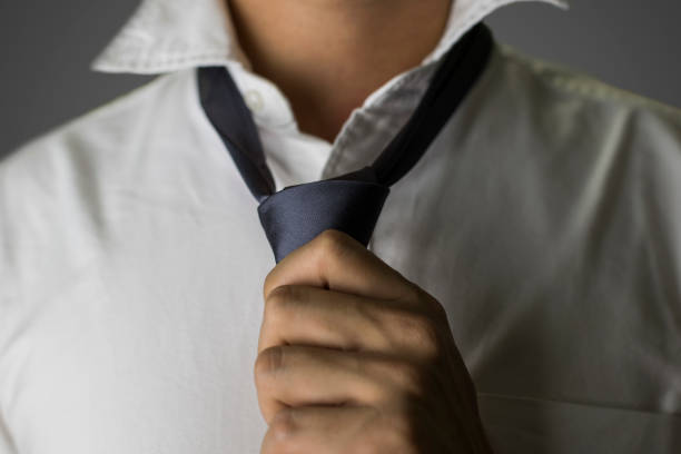 istock Close up on a man getting dressed in white shirt and grey necktie 654722882