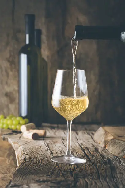 Wine. Glass of white wine in wine cellar. Old white wine on wood.