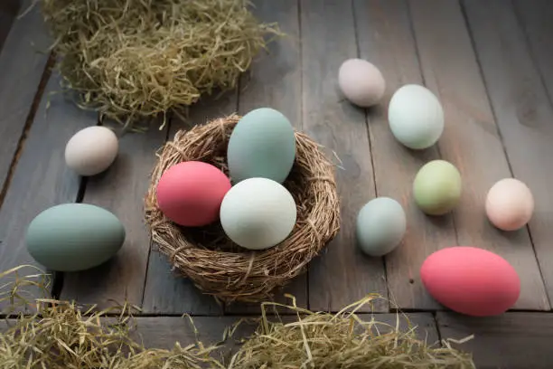 Decoration with colorful easter eggs in in a nest on a old shabby wooden table
