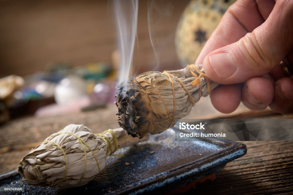 Man burning white sage incense Man's hand with burning natural white sage incense Smudged - Condition Stock Photo