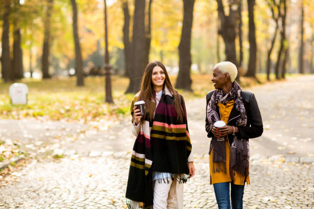 istock Two pretty young multiethnic female friends walking in park 654744902