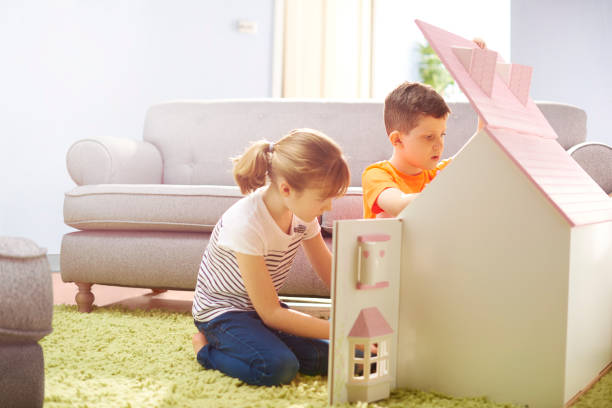 istock boy and girl playing with a dollhouse 654750886