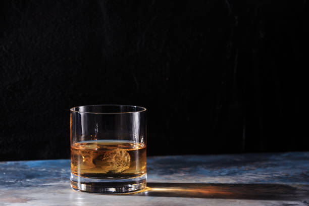 Glass of whiskey with ice on the table
