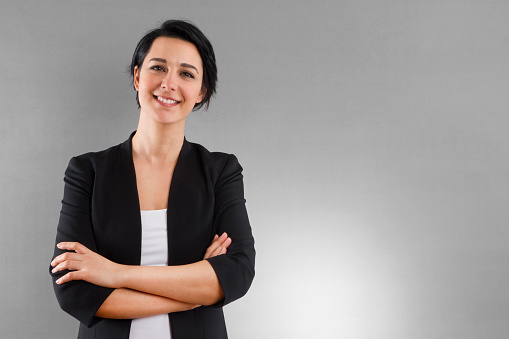 Young businesswoman standing infront of grey background with self confident