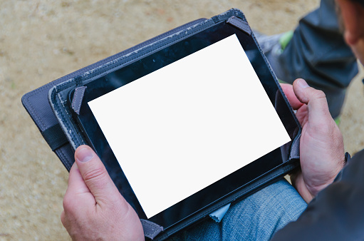 Unrecognizable man holding an used tablet pc in his hands. Using technology and communications outdoors