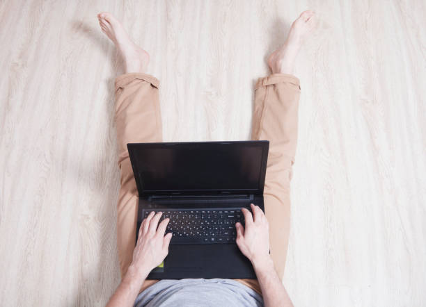 istock Young man sits on the floor with black laptop 654781718