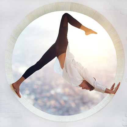 Young woman doing yoga in the round window