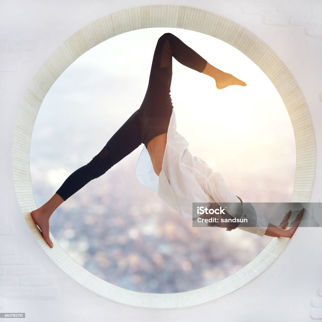 Young woman doing yoga Young woman doing yoga in the round window Flexibility Stock Photo