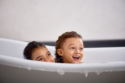 Cheerful girls looking with excitement at something, wet girls sitting in bathtub