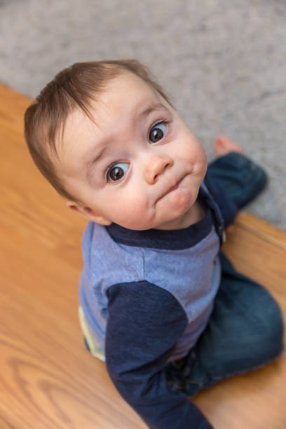 istock Baby Boy Sitting On Floor Looking Up 654805312
