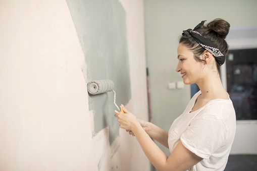 Happy young woman painting wall