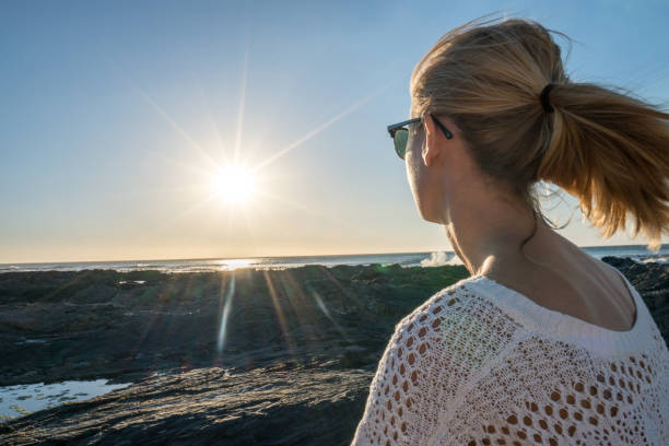 istock Young woman watching sunset by the sea 654815270