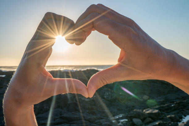 istock Heart shape finger frame on seascape at sunset 654815594