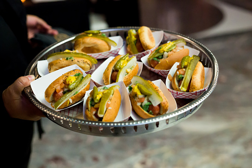 Server Holding A Tray of Mini Chicago Style Hot Dogs