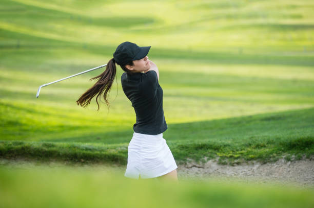 Young Hispanic Women Hitting The Ball Out Of A Bunker stock photo