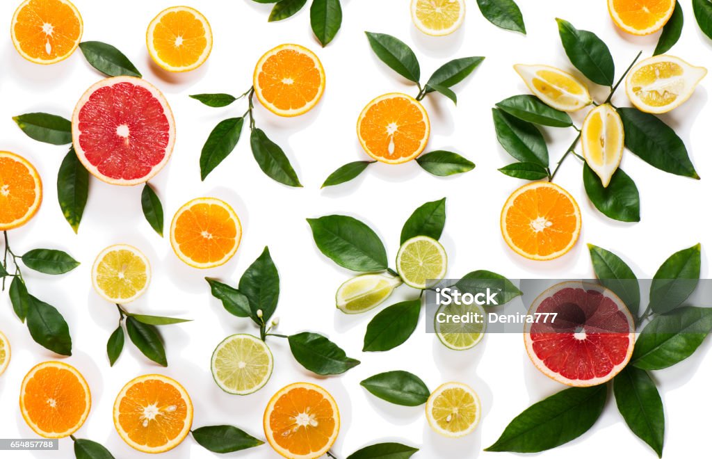 Background of citrus fruits Colorful pattern made of slices of citrus fruits (orange, lemon, lime, grapefruit) and green leaves isolated on white background. Grapefruit Stock Photo