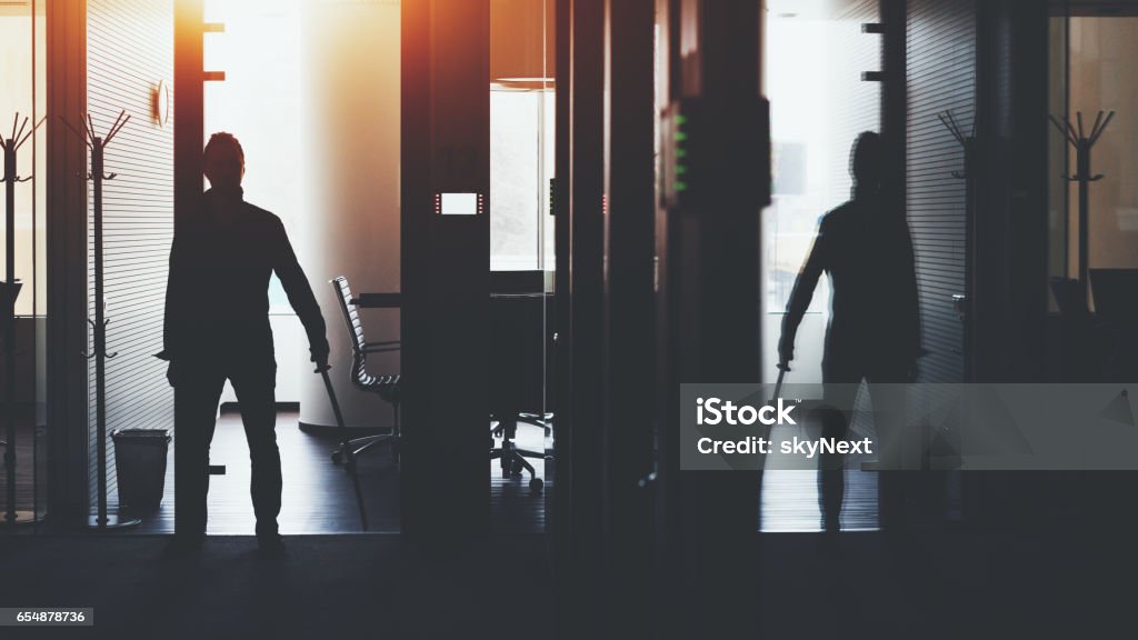 Businessman in office holding katana sword Silhouette of boss or businessman standing in dark office interior with a lot of reflections near meeting rooms and holding katana sword like japanese samurai warrior ready to defense or fight Murderer Stock Photo