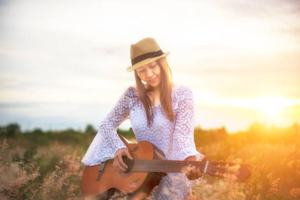 istock Woman playing the guitar in meadow 654905622