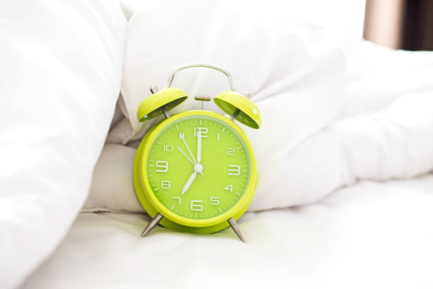 istock Alarm clock on bed in morning with sun light, Greenery ,soft and select focus 654913130
