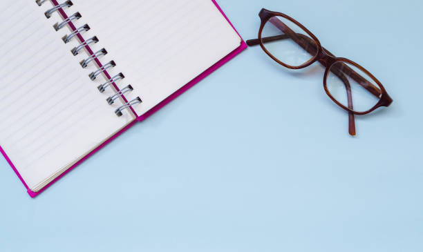 istock Eyeglasses and blank notebook on blue background from top viewpoint 654918254