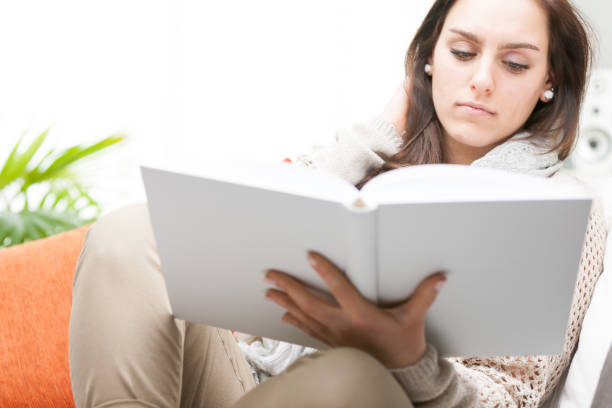 istock Attractive young woman reading a hardcover book 654920404