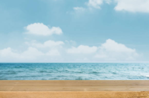 istock Empty wooden table top with blurred sea and sky background. 654928698