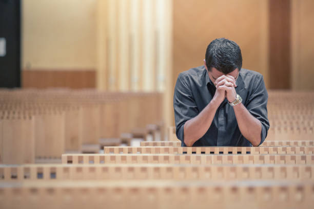 istock Young beard man wearing blue shirt praying in modern church 654943032