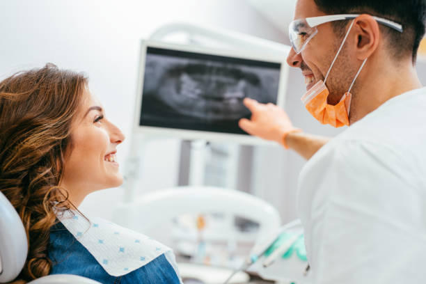 Dentist showing a patient her x-ray Dentist and patient looking at a digital dental x-ray. orthodontist consultation stock pictures, royalty-free photos & images