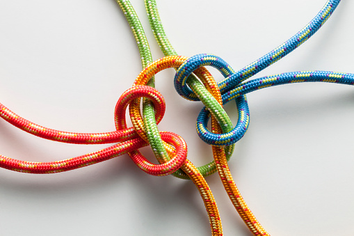 Four twisted ropes of different colors linked together in the middle.  The ropes are red, blue, yellow and green in color.