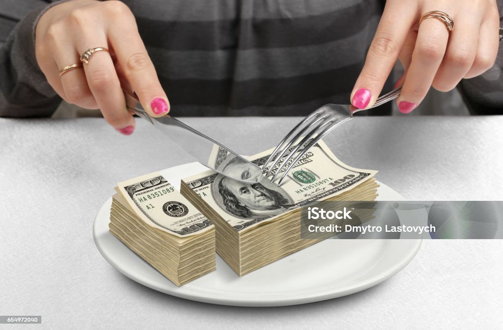 Hands cut money on plate, reduce funds concept Currency Stock Photo
