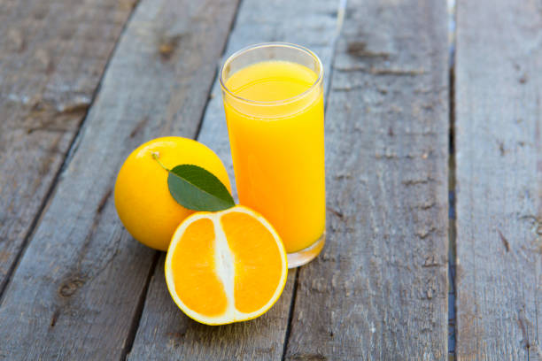 istock Orange juice with orange on table on wooden background 654981232