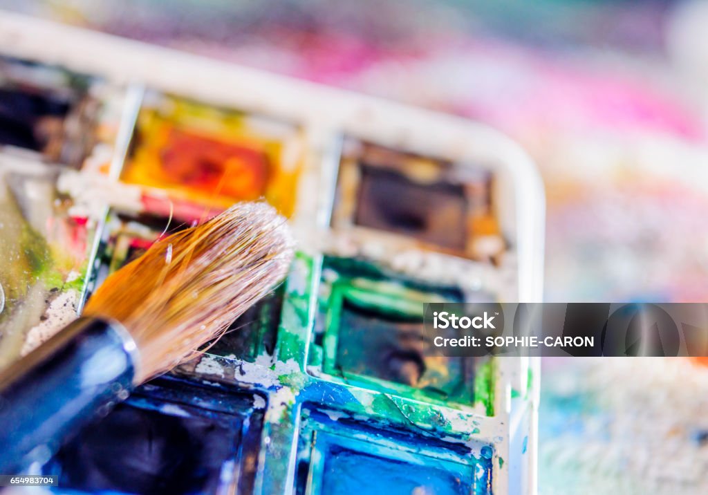 Watercolor pallette, brush A pallet of watercolor pellets on a cloth stained with paint. A brush is placed on the tray. Art Stock Photo