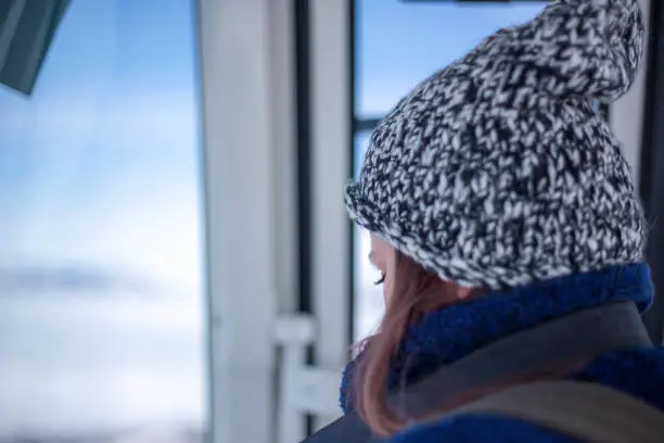 Rapt female rides on funicular in mountains.