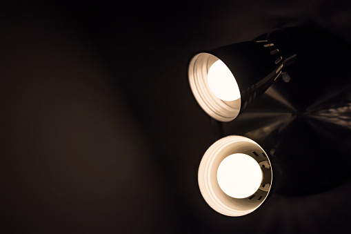 Two incadescent light bulbs in an industrial lamp. Dark environment. Concept of idea. Copy space on the left.