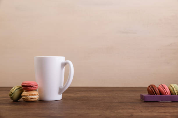 Macaroon cakes. Mockup white tea or coffee cup. Almond sweet cookies. Wooden rustic board.