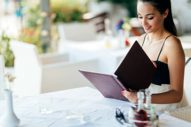 istock Beautiful woman ordering from menu in restaurant 655050090