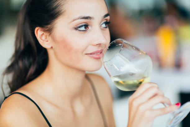 istock Beautiful woman tasting wine while sitting in restaurant 655050154