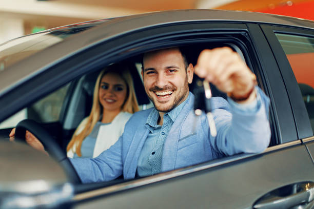 Pareja joven sosteniendo las llaves de un coche nuevo - foto de stock